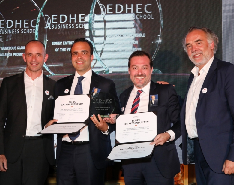 Quatre hommes souriants recevant des diplômes EDHEC Entrepreneur 2019 devant un écran de fond avec logo EDHEC Business Scho