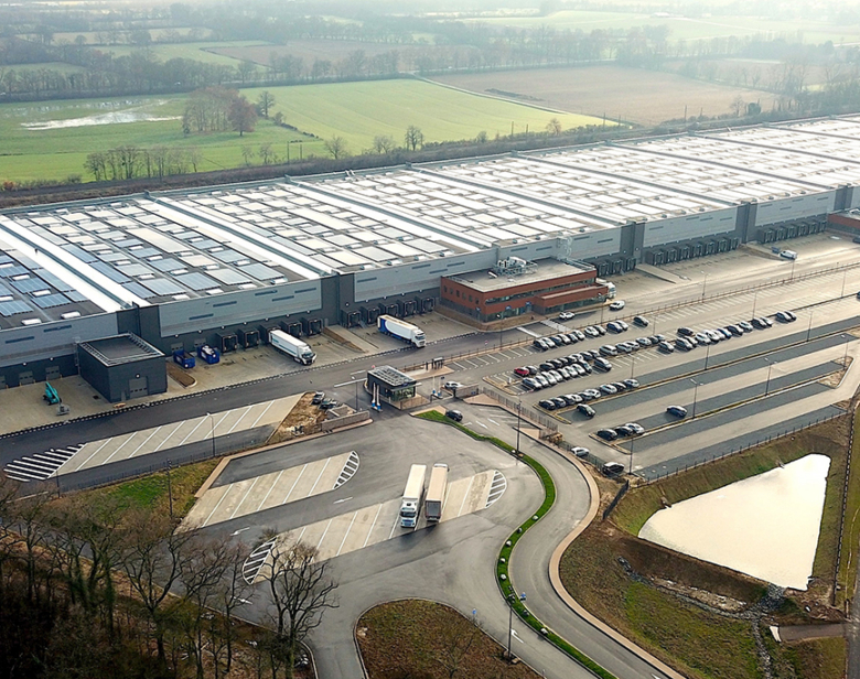 Vue aérienne d'un grand entrepôt industriel avec parking et accès routier pour camions et véhicules