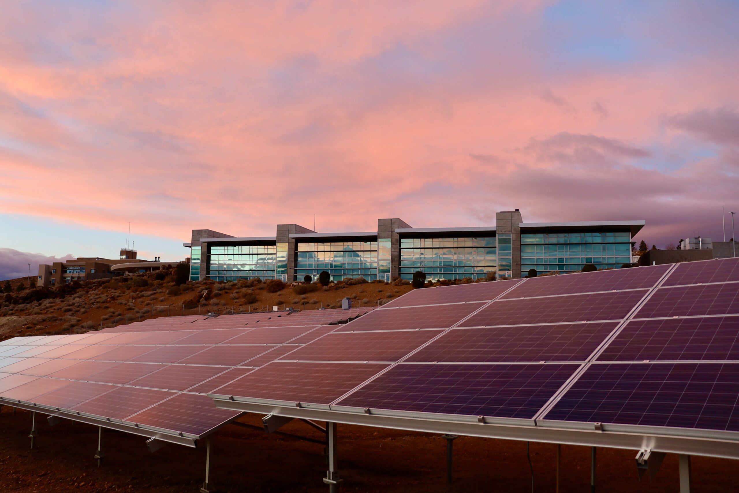 Installation solaire devant bâtiment moderne au coucher de soleil avec ciel coloré