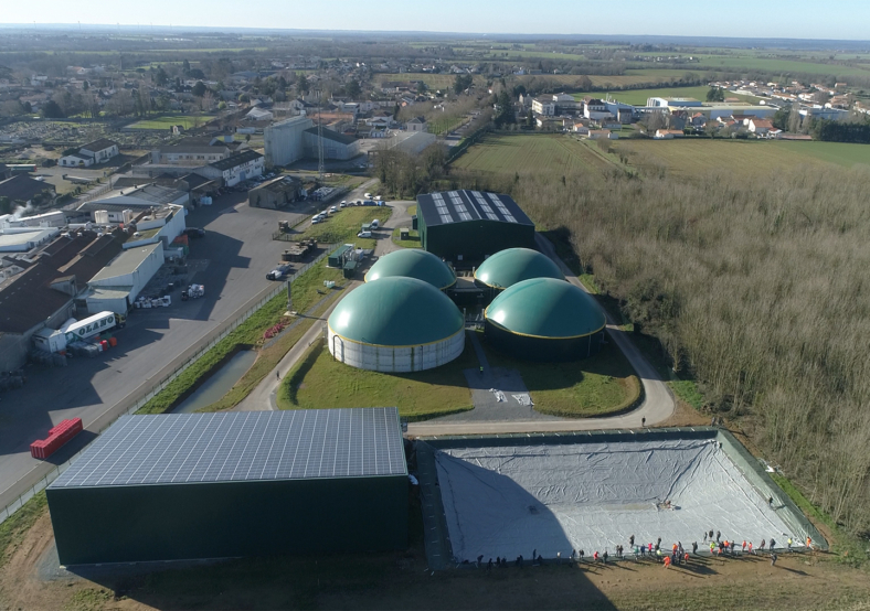Vue aérienne d'une installation industrielle avec digesteurs biométhane et panneaux solaires dans un paysage rural