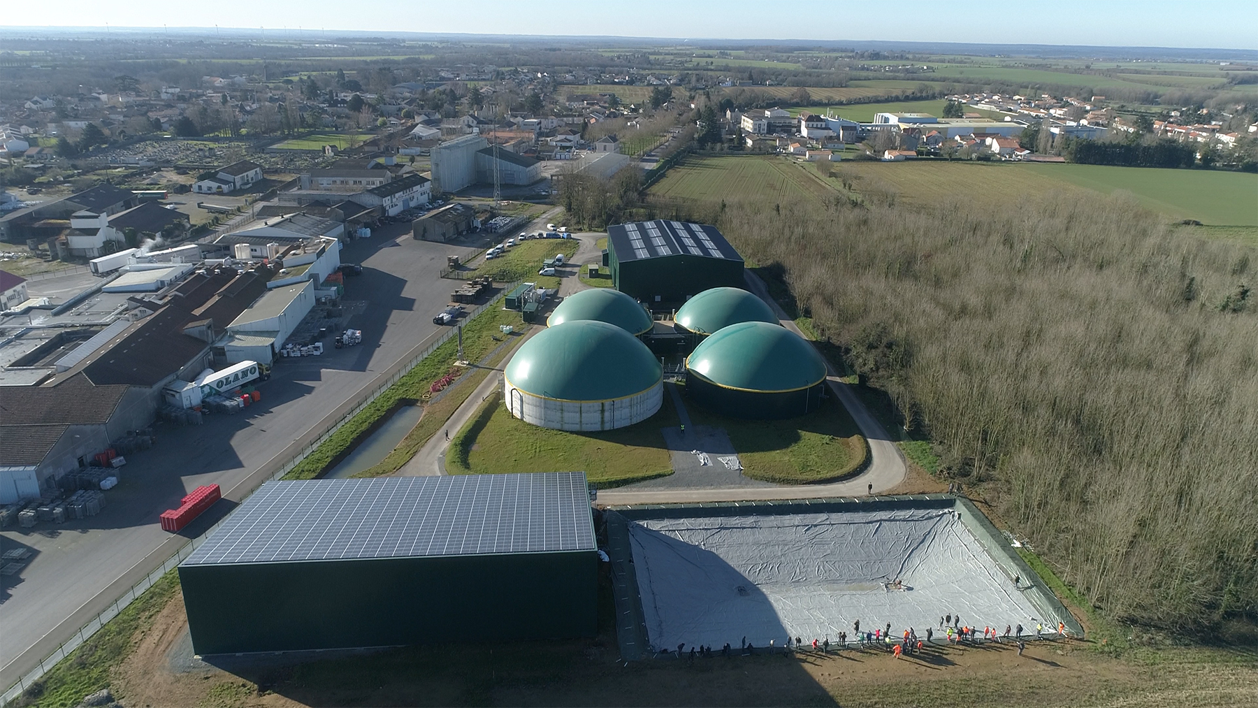 Vue aérienne d'une installation industrielle avec digesteurs biométhane et panneaux solaires dans un paysage rural