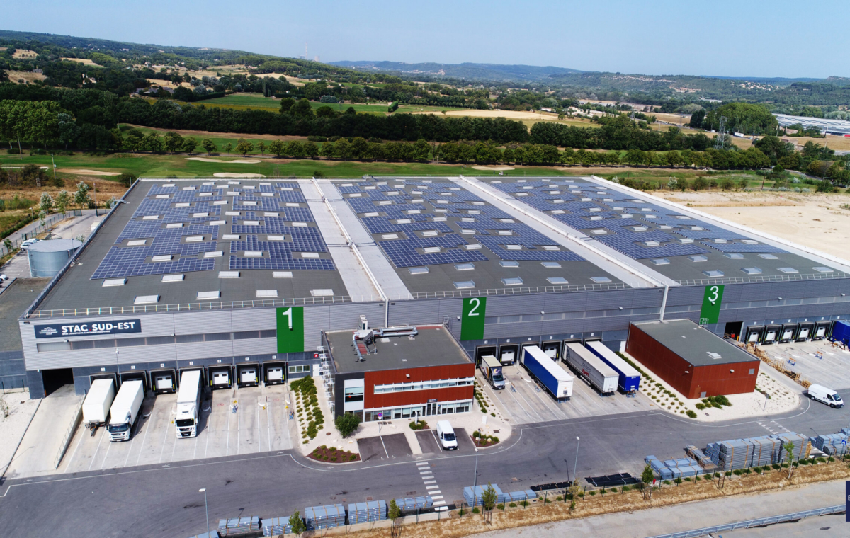 Vue aérienne d'un entrepôt solaire STAC Sud-Est avec trois zones de chargement et véhicules de livraison