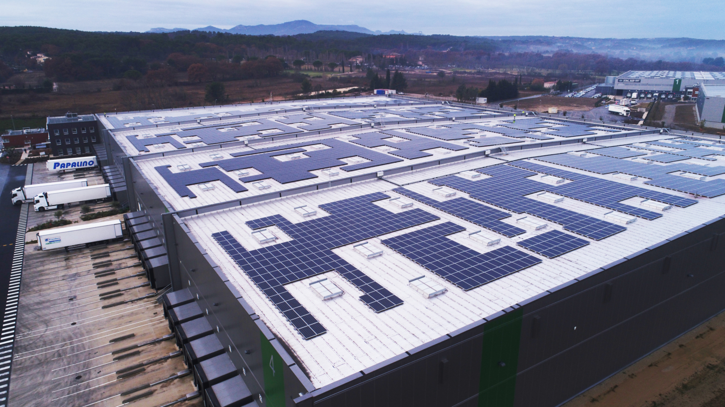 Installation photovoltaïque couvrant une vaste surface industrielle avec toiture équipée de panneaux solaires dans un envi