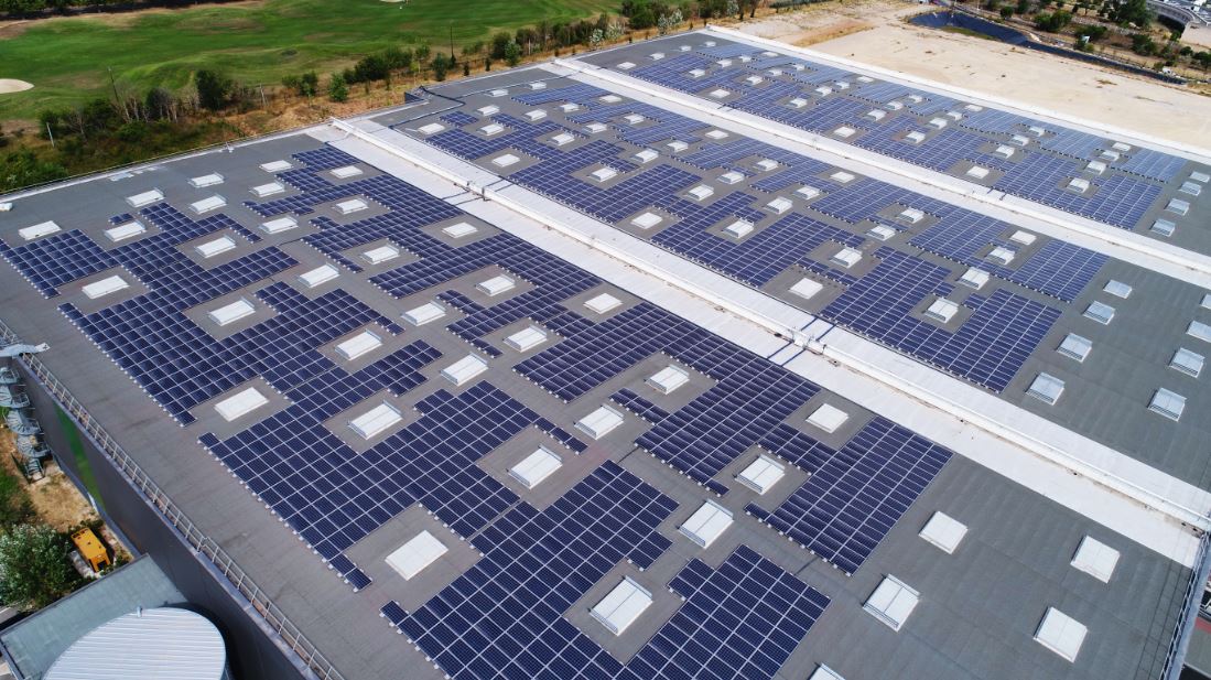 Installation photovoltaïque couvrant une vaste toiture industrielle avec des panneaux solaires alignés de manière méthodi