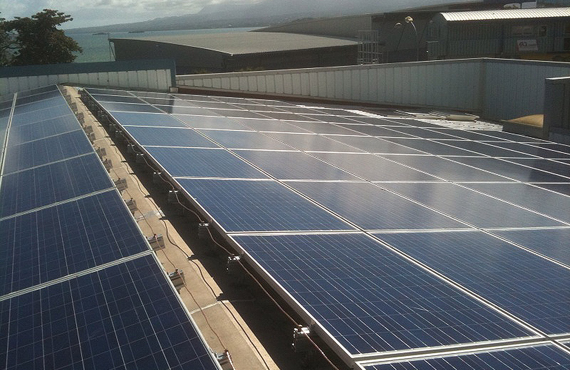 Toit équipé de panneaux solaires photovoltaïques avec vue sur un paysage maritime et des bâtiments à l'arrière-plan