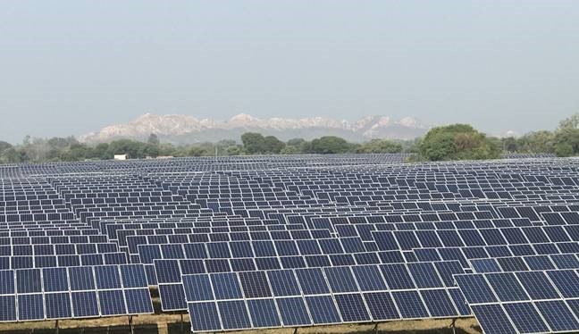 Champ de panneaux solaires photovoltaïques avec montagnes en arrière-plan sous ciel dégagé
