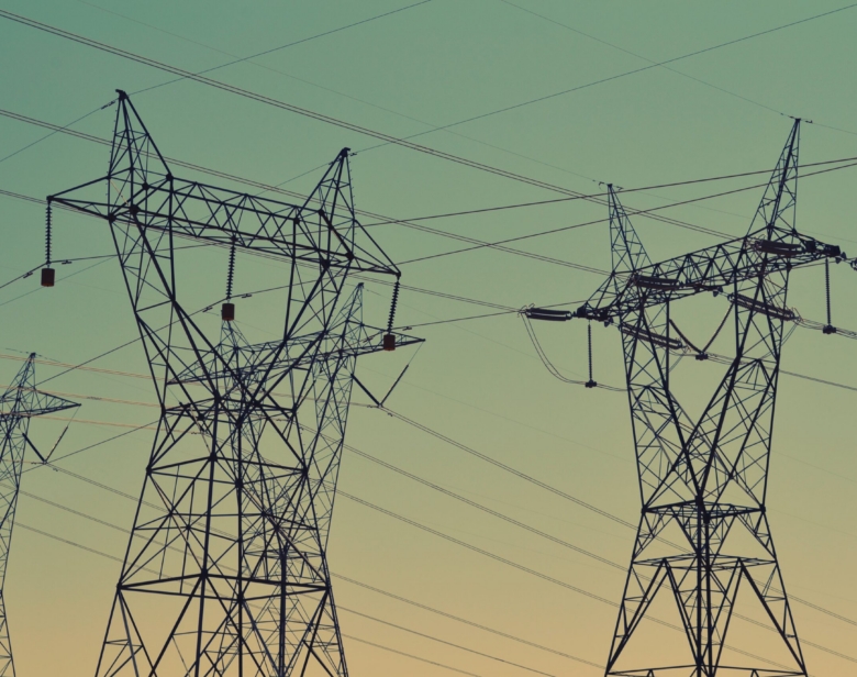 Pylônes électriques métalliques transportant des lignes haute tension contre un ciel clair