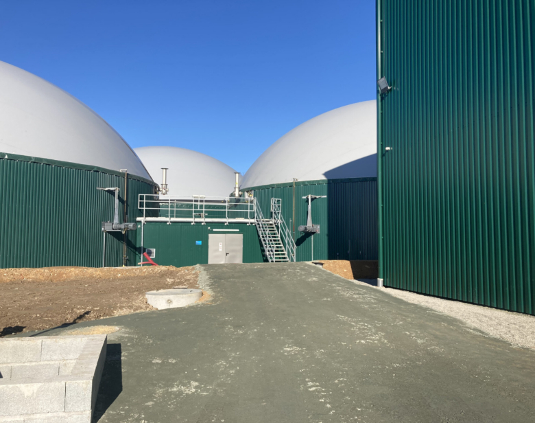 Installation de biodigesteurs avec réservoirs blancs et structure métallique verte pour traitement de déchets organiques