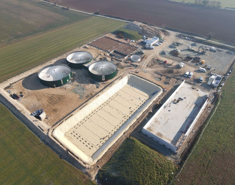 Chantier agricole avec silos à grain et bâtiments en construction entourés de champs et de zones en préparation