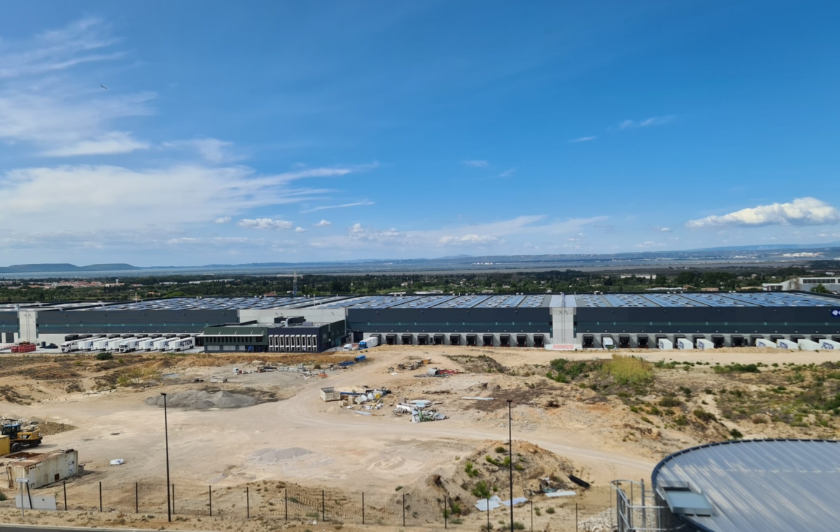 Vue aérienne d'un vaste chantier industriel avec bâtiments en construction et terrain en préparation