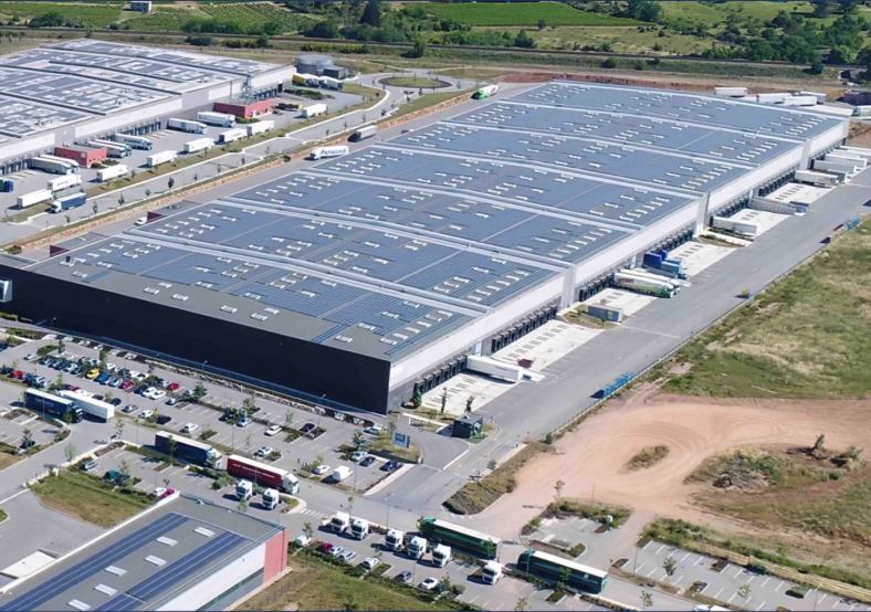 Vue aérienne d'un grand complexe industriel avec entrepôts et parkings associés