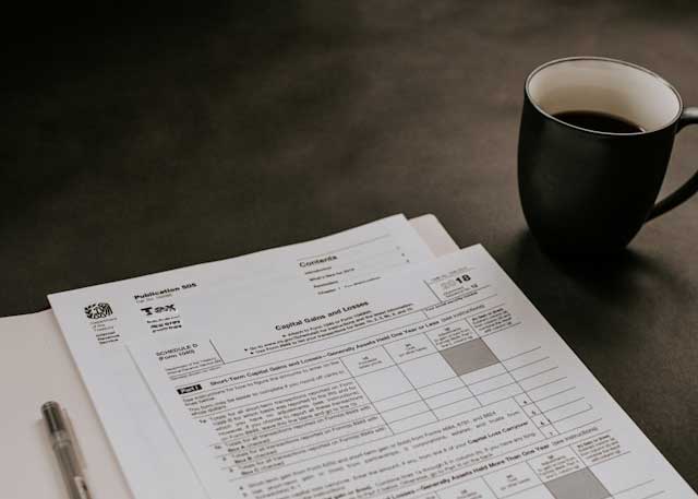 Formulaire fiscal pour déclarer les gains et pertes en capital avec une tasse de café à côté et un stylo