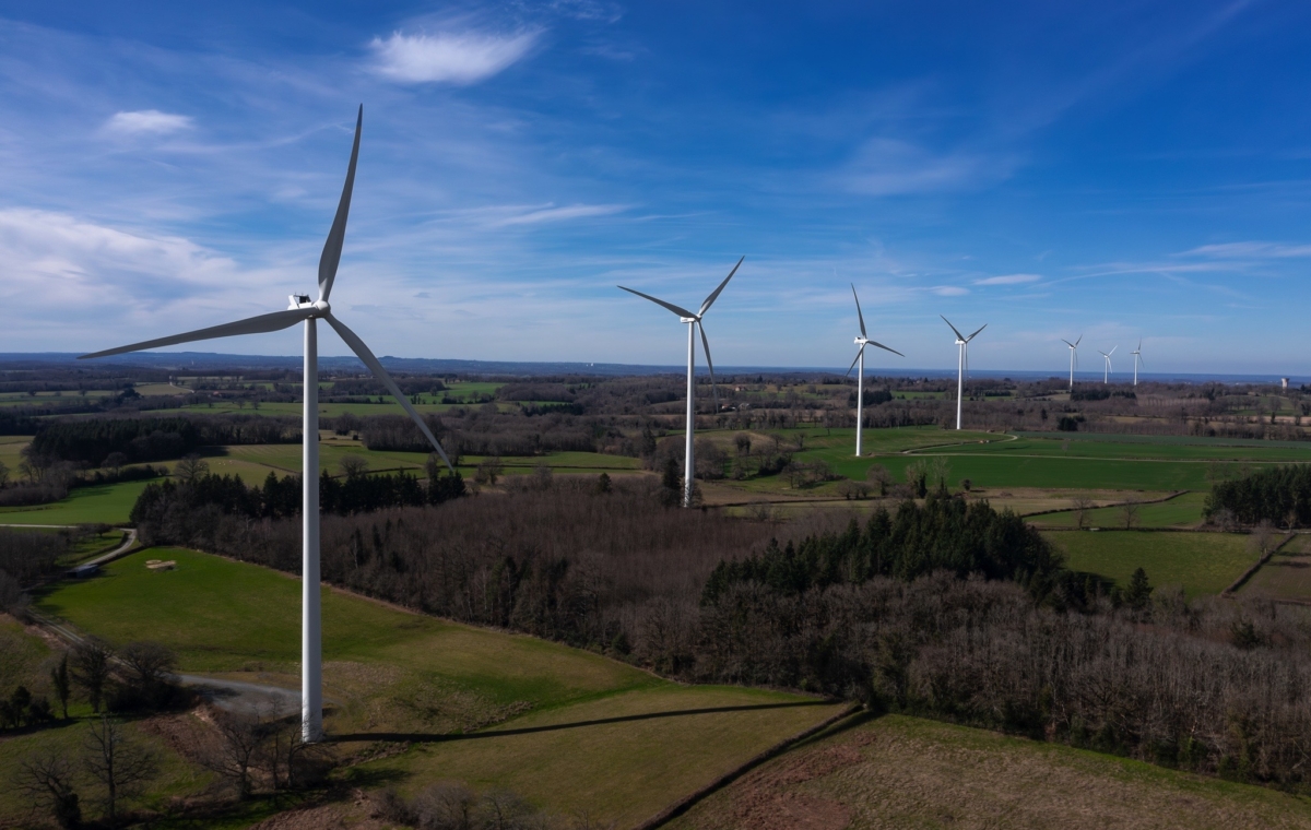Parc éolien avec plusieurs éoliennes sur un paysage rural verdoyant et vallonné sous un ciel dégagé