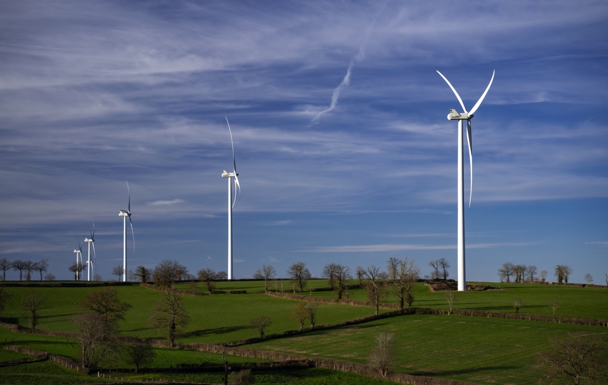 Éoliennes sur un paysage verdoyant avec ciel dégagé et quelques nuages
