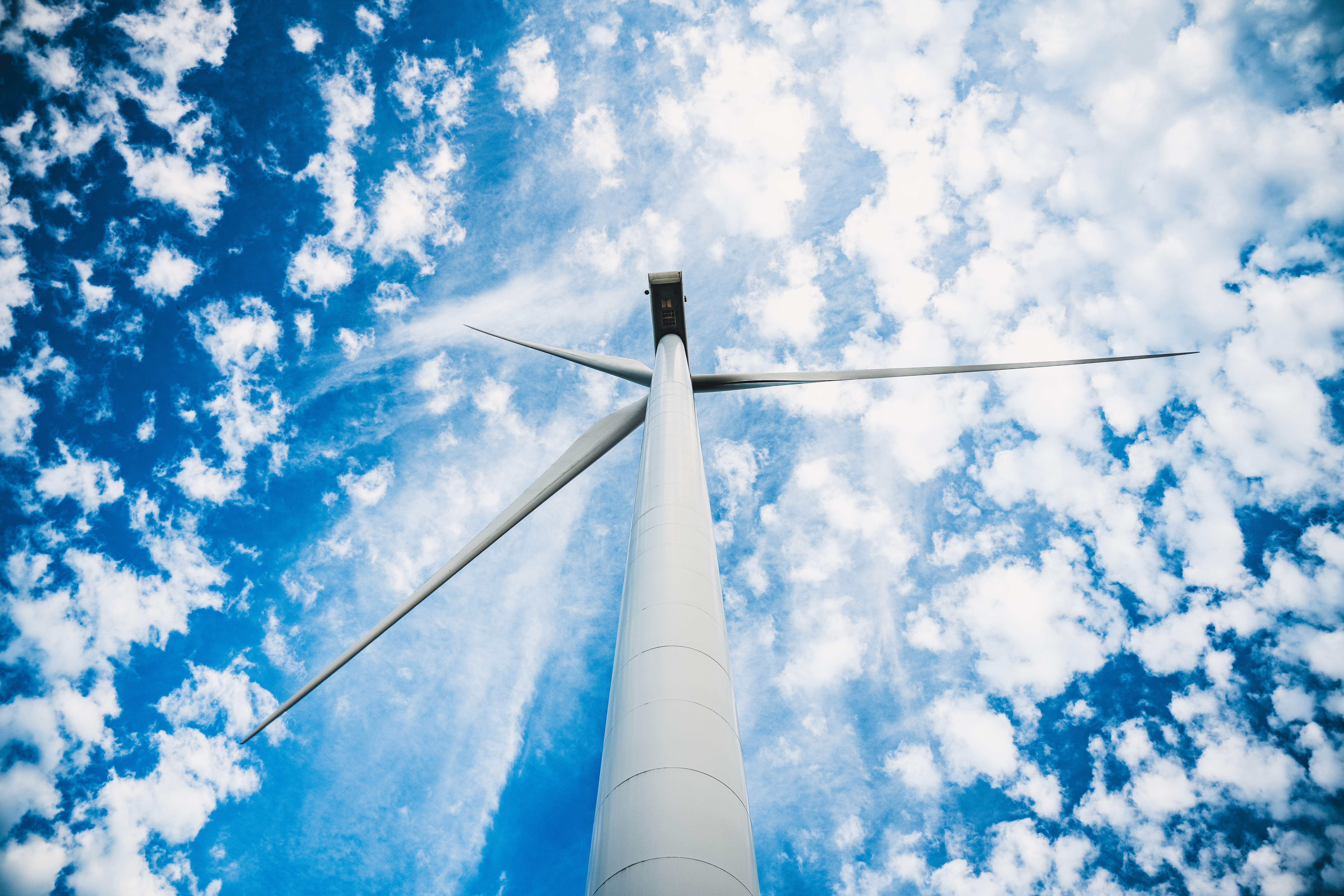 Éolienne vue de dessous avec ciel bleu et nuages floconneux