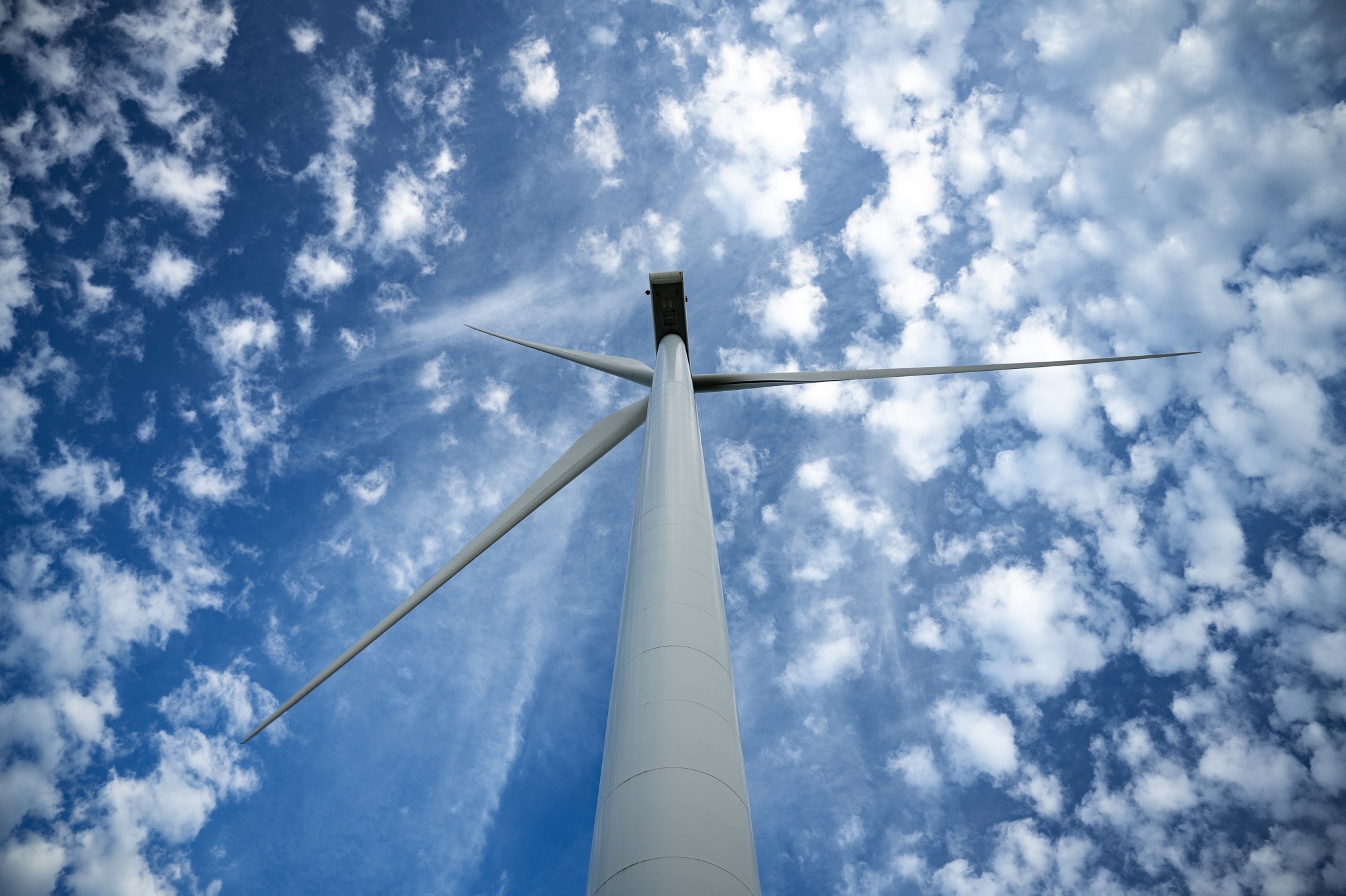 Éolienne avec pales étendues sous un ciel bleu parsemé de nuages