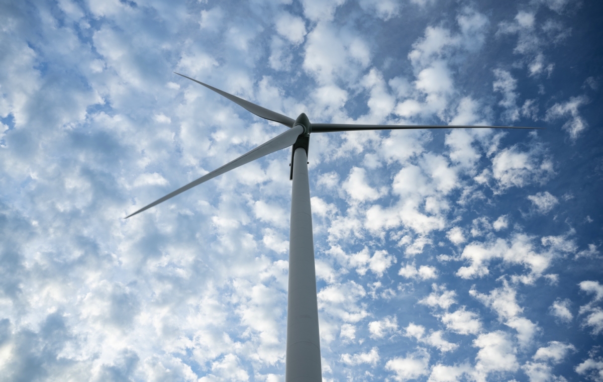 Éolienne moderne s'élevant vers un ciel bleu parsemé de nuages captant l'énergie renouvelable par le vent