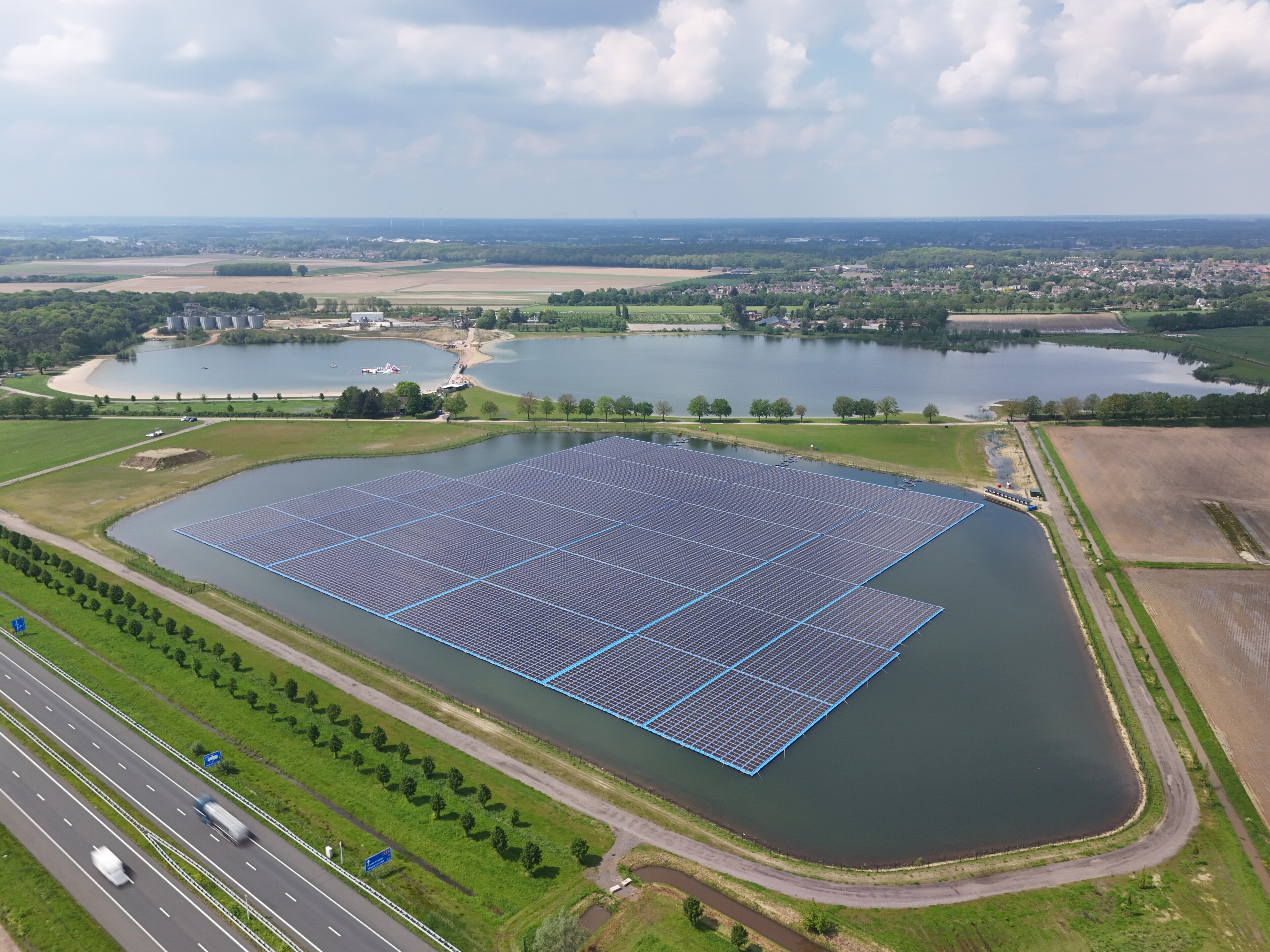 Vue aérienne d’un site innovant combinant agriculture et énergies renouvelables près d’un lac et de champs
Un projet d