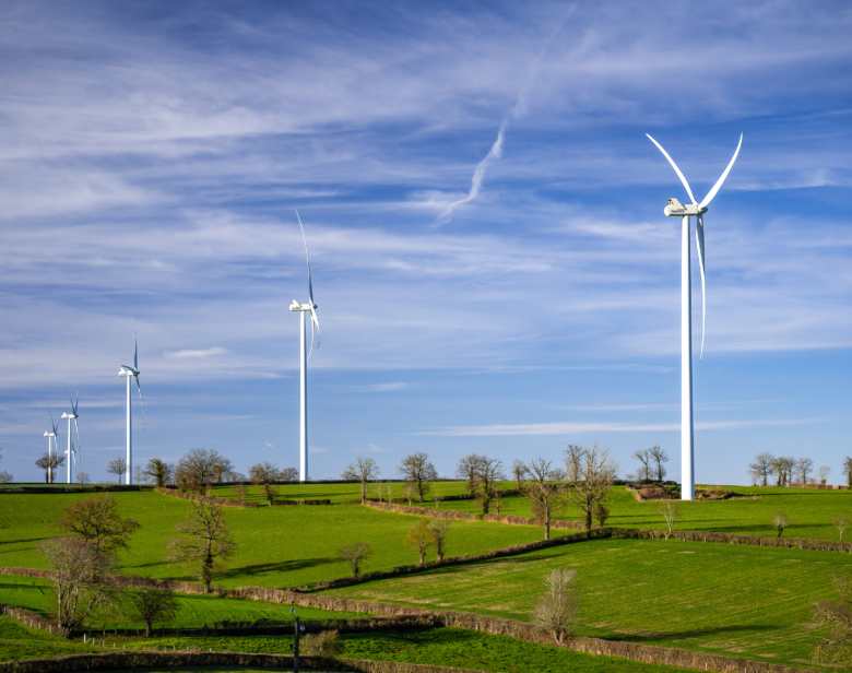 Parc éolien moderne s’étendant sur des collines verdoyantes sous un ciel dégagé illustrant l’énergie renouvelable pa