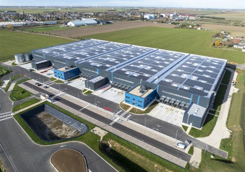 Vue aérienne d’un vaste complexe industriel équipé de toitures photovoltaïques en pleine campagne, illustrant une solut