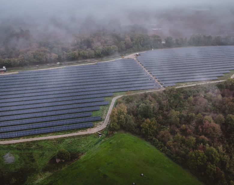 Parc solaire moderne intégré dans un environnement naturel boisé sous brume légère illustrant une installation photovolt
