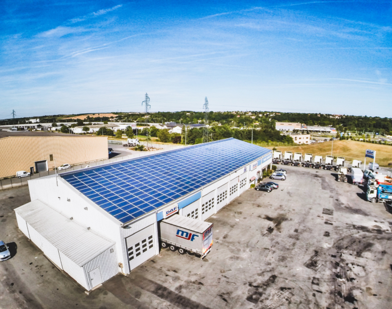 Atelier industriel équipé de toiture photovoltaïque avec véhicules utilitaires et entrepôts environnants dans une zone l
