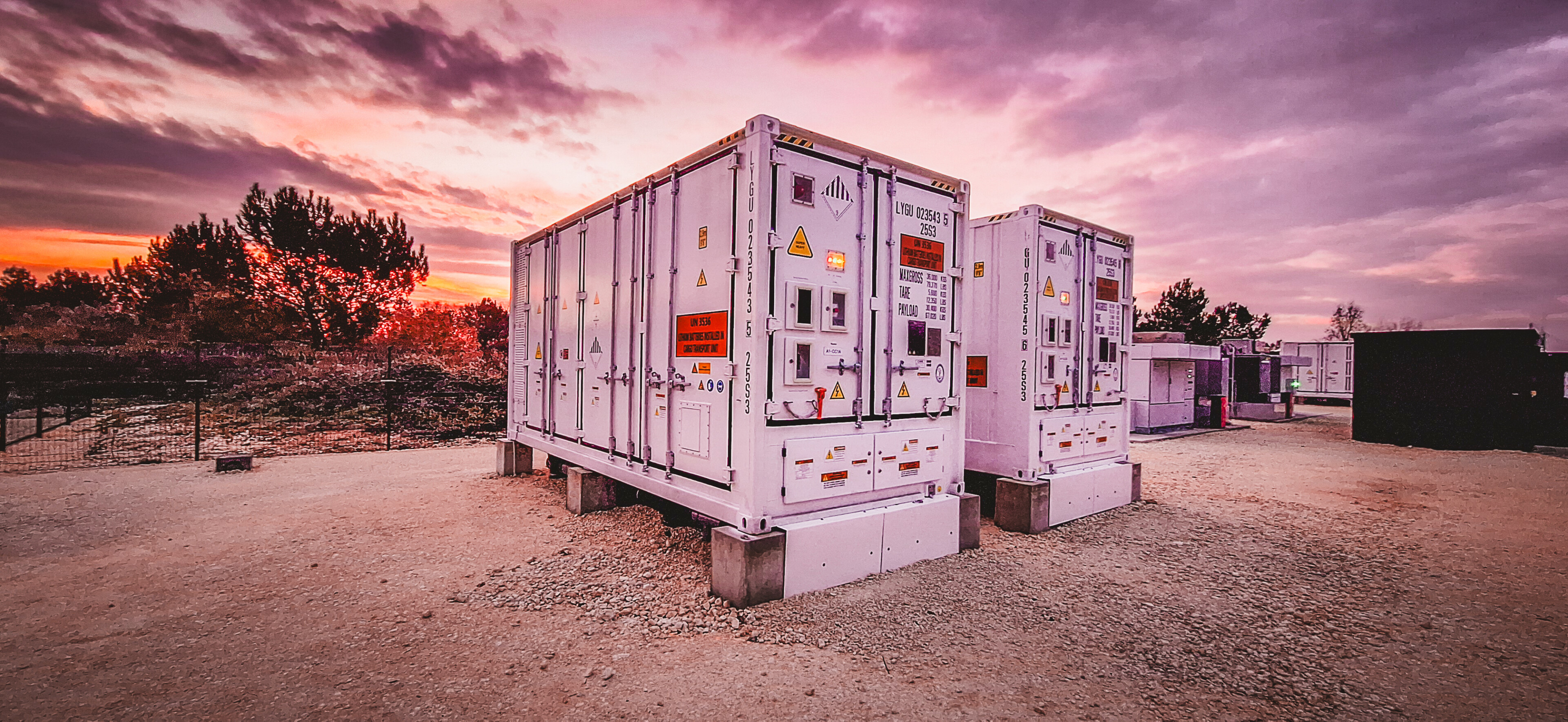 Conteneurs électriques industriels installés en extérieur lors d’un coucher de soleil dans un site technique ou agricole