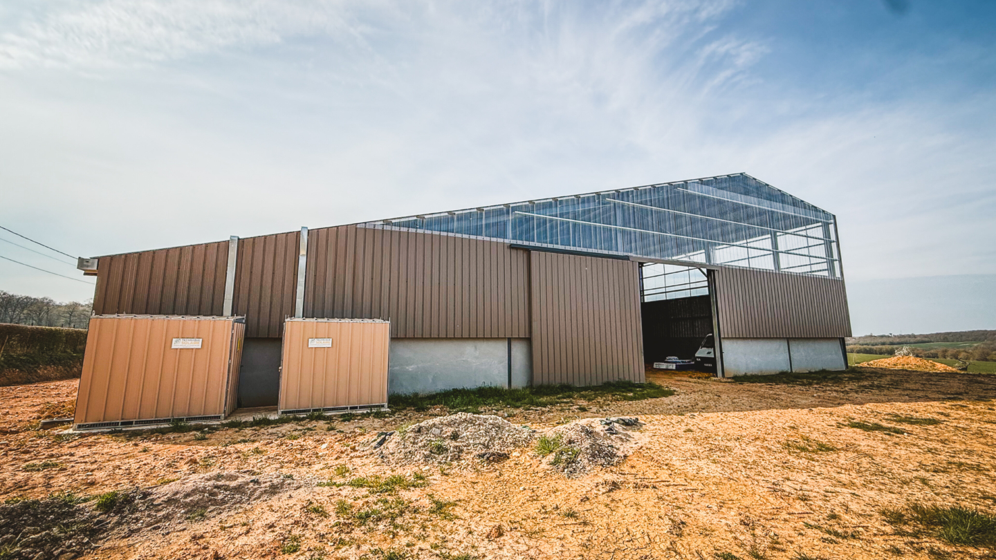 Bâtiment agricole moderne avec structure métallique et toiture équipée d’un système d’agrivoltaïsme intégrant pann