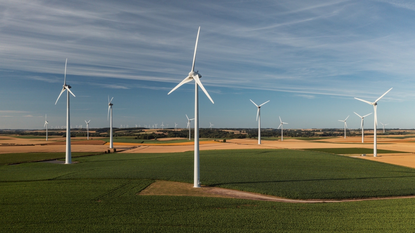 Parc éolien moderne s’étendant dans un paysage agricole verdoyant sous un ciel dégagé illustrant les énergies renouvel