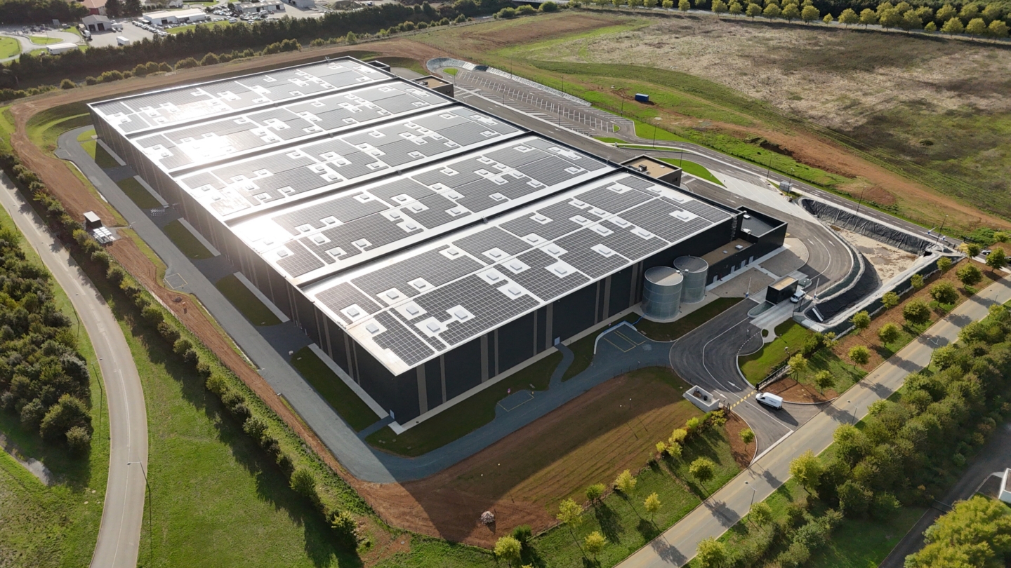 Vue aérienne d’un grand bâtiment industriel équipé d’une imposante installation de toiture photovoltaïque dans un en