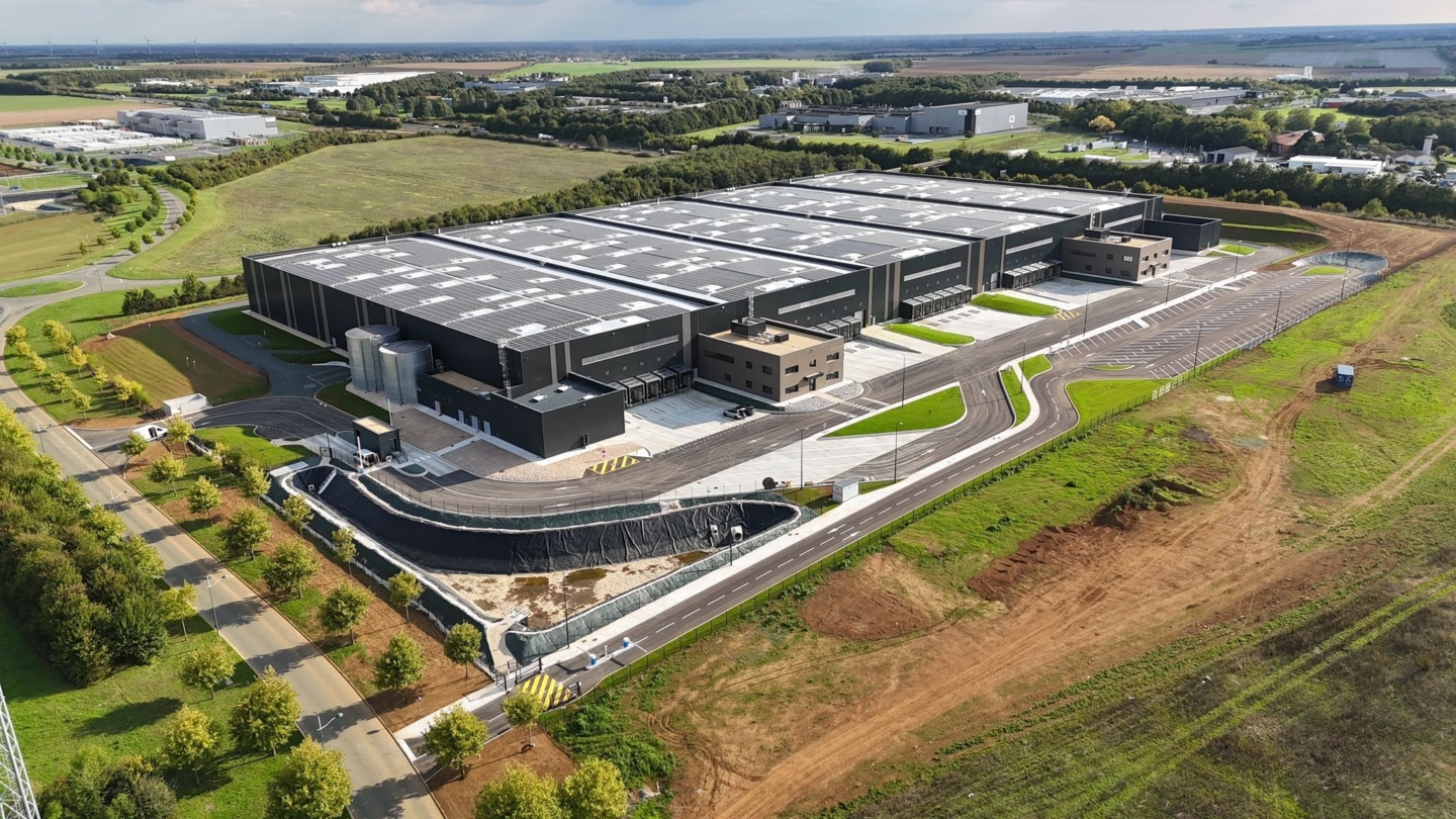 Vue aérienne d’un vaste complexe industriel moderne avec toiture photovoltaïque intégrée dans une zone rurale entourée